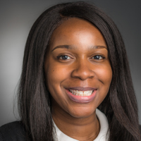 Portrait of a smiling researcher with long dark hair, wearing a collared shirt.