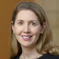Portrait of a smiling researcher with long hair and pearl earrings, likely affiliated with cancer research.