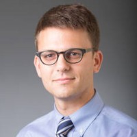Portrait of a researcher in a collared shirt and glasses.