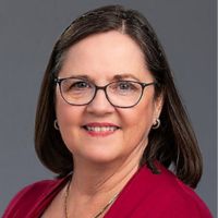 Portrait of a woman with glasses and shoulder-length hair, wearing a red blouse.